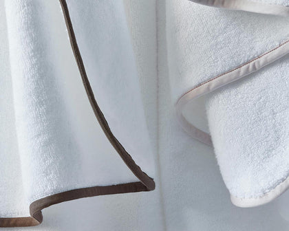 White Giza towels hanging with brown and tan piped trim.