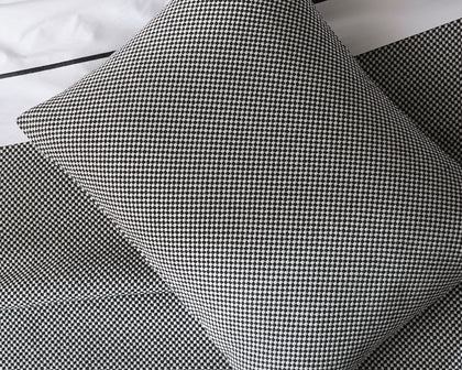 Black and white Jackson houndstooth-textured pillow and sheets, styled on a bed.