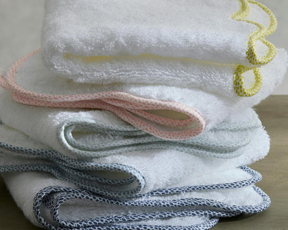 White Jasper towels with pebbled trim in yellow, pink, and gray, folded in a stack.
