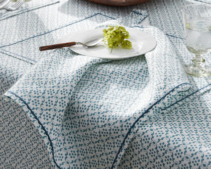 Blue Laksha medallion print tablecloth and napkin set with a white plate and green hydrangea.