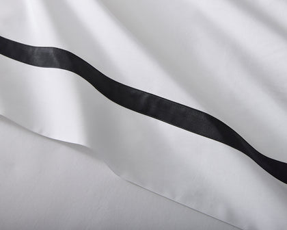 White Lowell bedding with a black ribbon trim.