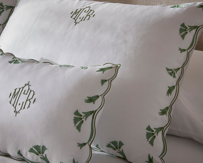 White monogrammed Marcella pillows with a green vine-embroidered scalloped border.