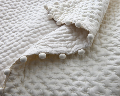 Ivory Margaret textured quilted bedding with a pompom trim edge.