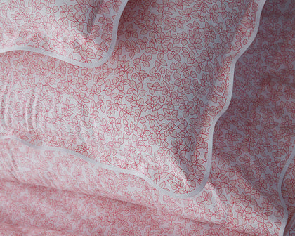 Pink Margot vine-print scalloped bedding, styled on a bed.