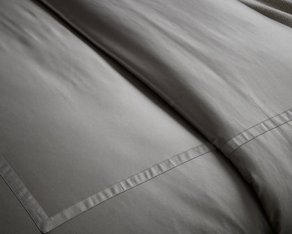 Gray Nocturne sateen sheets folded on a bed.