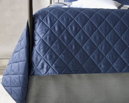 Navy diamond-quilted Nocturne Quilt coverlet on a four-poster bed.
