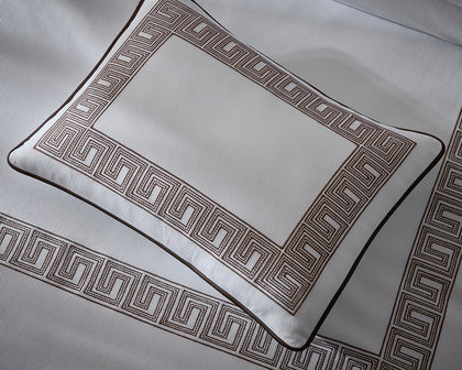 White Ophelia Pique pillow sham with brown Greek key border on matching textured bedding.