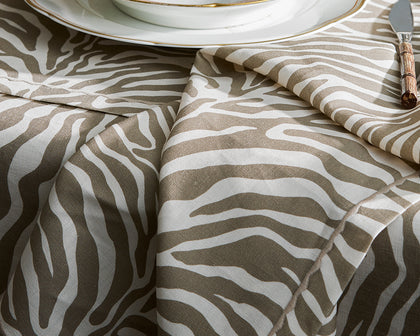 Taupe zebra-print Regine tablecloth and napkin styled with a gold-rimmed plate.