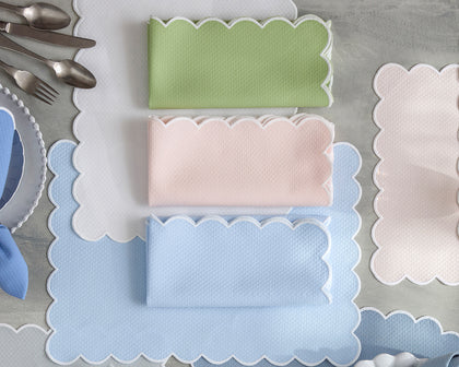 Scalloped-edge Savannah Gardens placemats and folded napkins in green, pink, and blue.