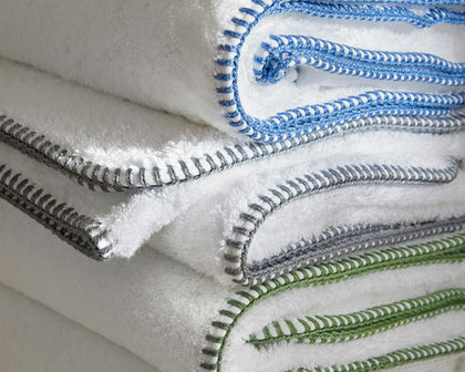 White Whipstitch towels with blue, gray, and green whipstitch trim stacked together.