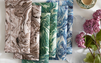 Balthazar marbled-print napkins stacked in blue, gold, and green with fresh hydrangeas