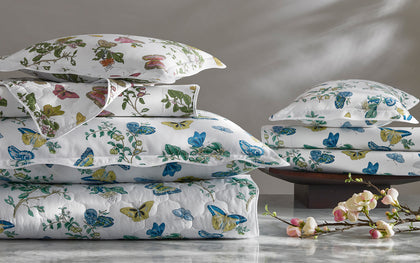 White Baudin Butterfly print bedding stacked with blue, green, and gold butterflies on a marble surface.