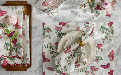 Baudin Butterfly print placemats and napkins with pink florals and butterflies, set with a scalloped plate.