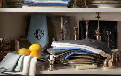 Monogrammed Chamant linen napkins stacked with silver candlesticks and lemons