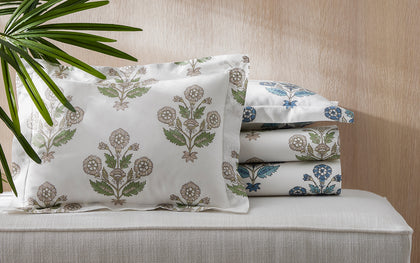 Green and blue Dalila floral print bedding stacked on a bench.