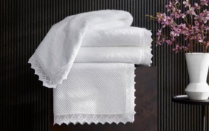Ellis white lace-trim towels stacked with an orchid branch