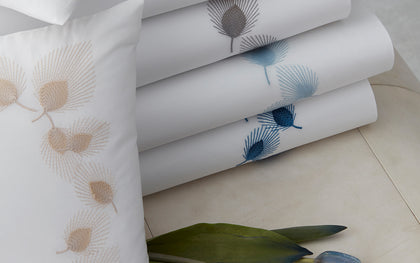 White Feather bedding embroidered with feather motifs in gold, gray, and blue.