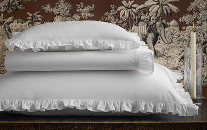 White Georgia ruffled pillow shams stacked on a dark table.
