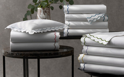 White India Pique scalloped sheets stacked with colorful trim, near a eucalyptus plant.