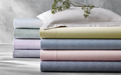 Jasper pebbled print sheets stacked in pastel colors, topped with a dried flower sprig.