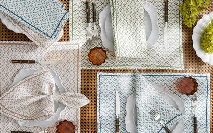 Laksha medallion print placemats and napkins in blue, green, and tan, set with scalloped plates and bamboo flatware.