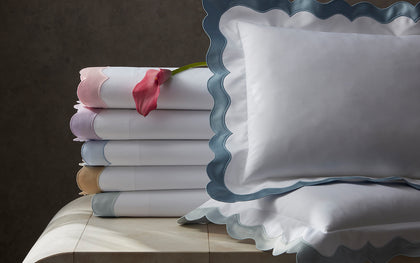 White Lorelei scalloped sheets in colorful trim, stacked with a pink calla lily.