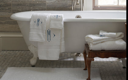 White monogrammed Lotus towels draped over a clawfoot tub.