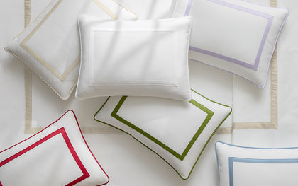 White Louise Pique pillows with bordered trim in red, green, lavender, and tan, arranged flat.