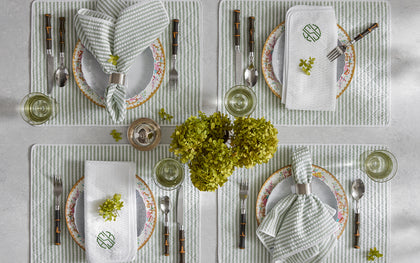 Green-striped Matteo placemats and napkins set for four with floral china and fresh hydrangeas.