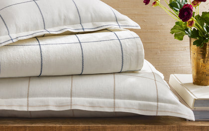 Sebastian windowpane-embroidered white linen bedding stacked with flowers