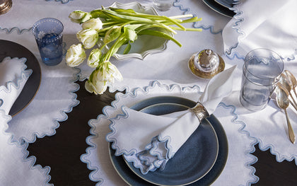 Wave table linens styled with blue scalloped-edge placemats and white tulips