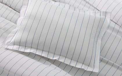 White Amalfi pinstripe pillow shown flat on matching bedding.