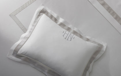 White Ambrose monogrammed pillow with satin bordered trim, shown flat.