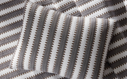 Gray Apollo Stripe Matelasse quilted pillow shown in detail on matching bedding.