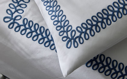 White Astor Braid pillows with navy loop-embroidered trim.