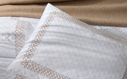 White Astor Braid quilted pillow with tan loop-embroidered trim, shown in detail.