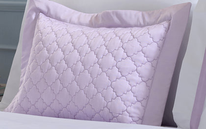 Lavender Ava quatrefoil-quilted pillow styled on a bed.