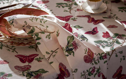 Baudin Butterfly print tablecloth with pink butterflies and florals, set with gold-rimmed china.