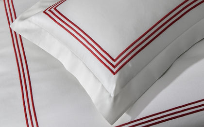White Bel Tempo Nocturne pillow with red triple-stripe embroidered trim, shown in detail.
