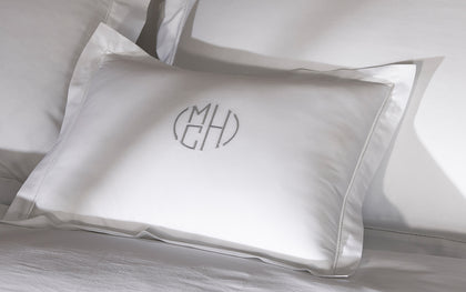 White Bergamo Hemstitch monogrammed pillow with hemstitch trim, styled on a bed.