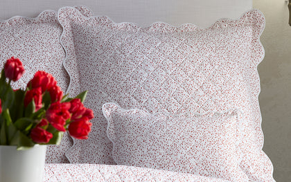 Red Celine speckled-print quilted bedding styled on a bed with red tulips.