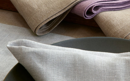 Gray Chamant linen napkin and placemat set on a dark plate.