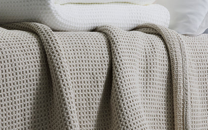 Gray waffle-weave Chatham blanket draped over a bed.