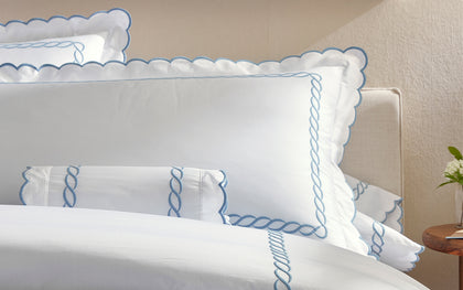 White Classic Chain Scallop bedding with blue scalloped chain-embroidered trim, styled on a bed.