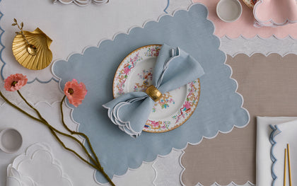 Blue Dakota scalloped placemat set with a floral plate and gold napkin ring.