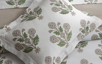 Green Dalila floral print pillow styled on a woven bed.