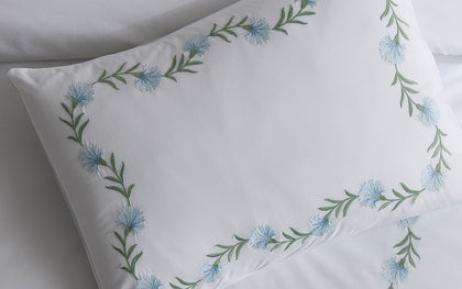 White Daphne pillow with blue floral vine embroidery.