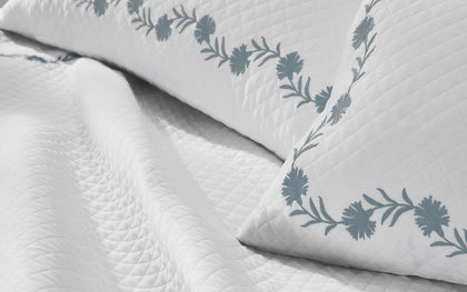 White Daphne Matelasse quilted pillow with slate blue floral vine embroidery.