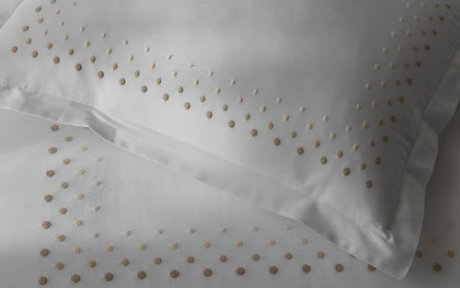 White Dorothy sheets with gold polka-dot embroidery.