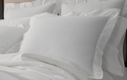 White Gatsby hemstitch pillows arranged on a bed.